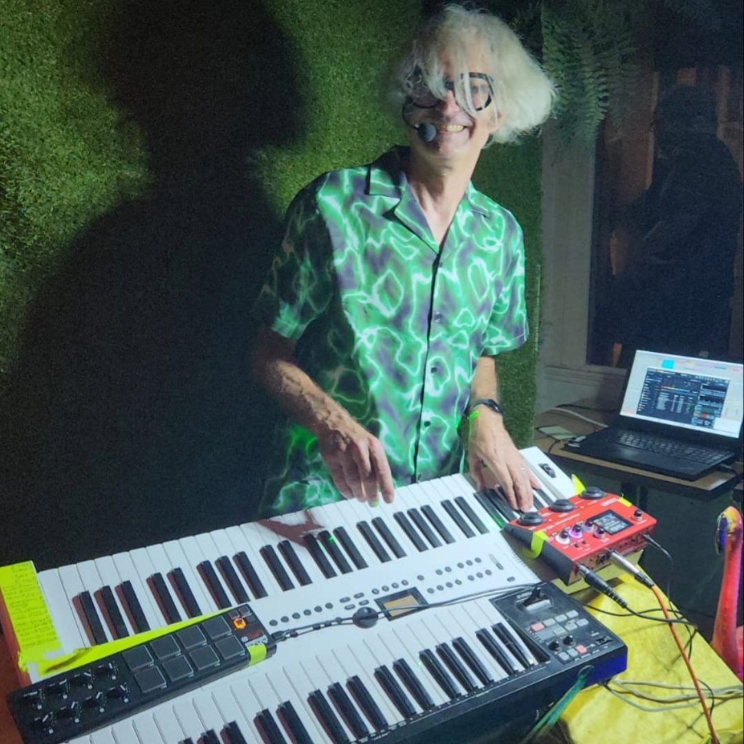 Monsieur Orange au clavier, chemise verte, micro-casque